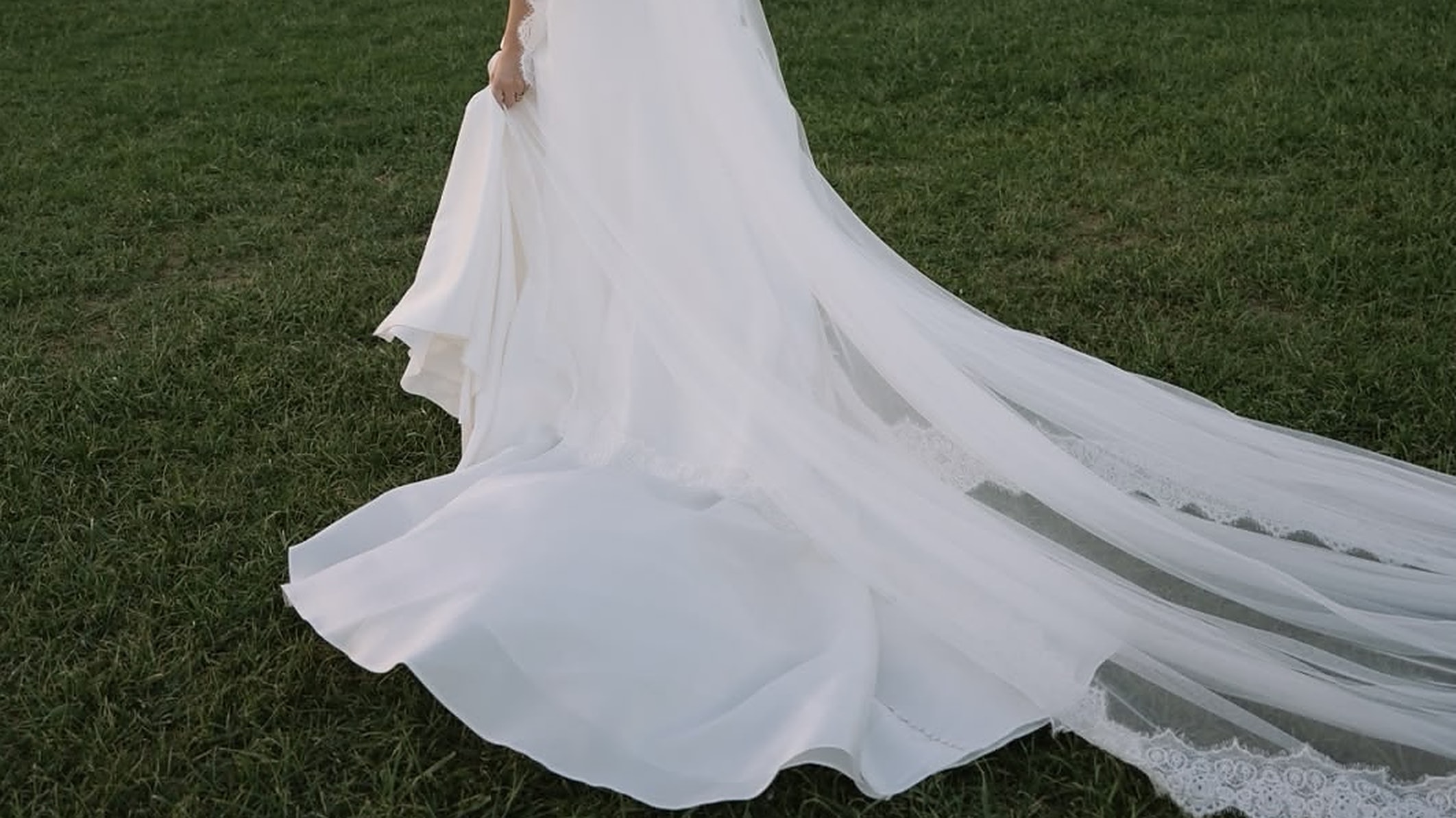 Bride's gown and veil trailing across the grass