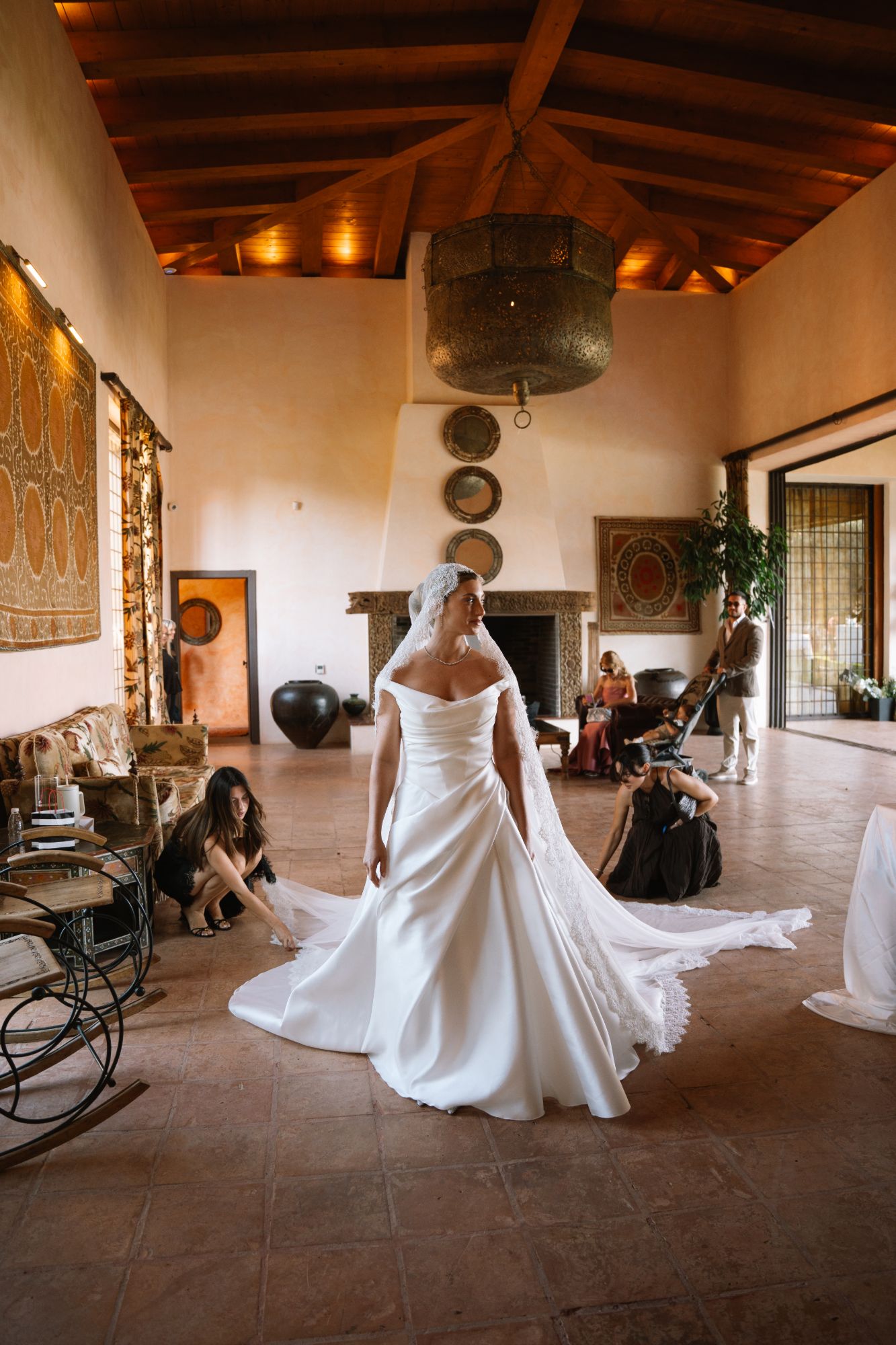 Bride in a sunlit hall while her veil is arranged