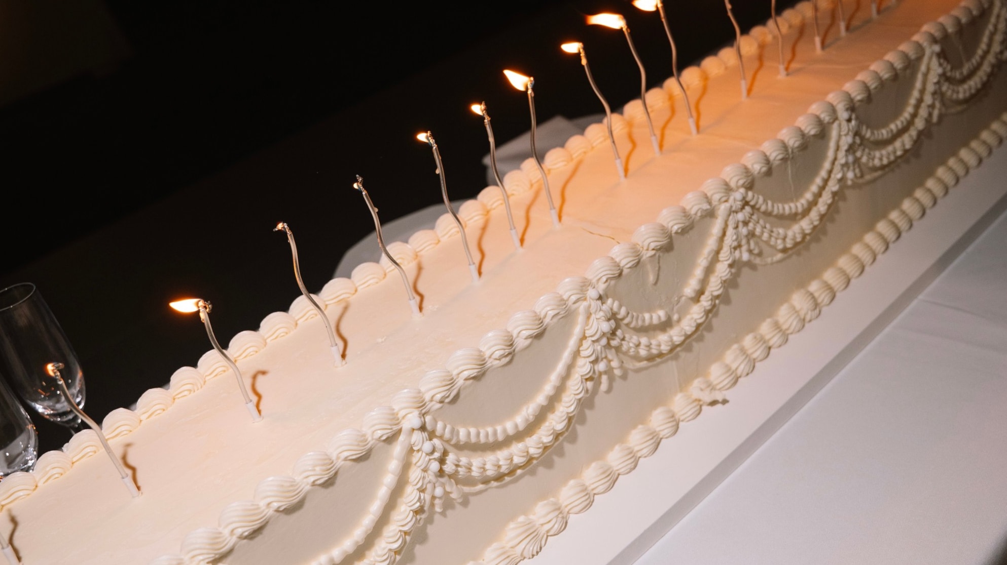 Long wedding cake with a row of lit candles